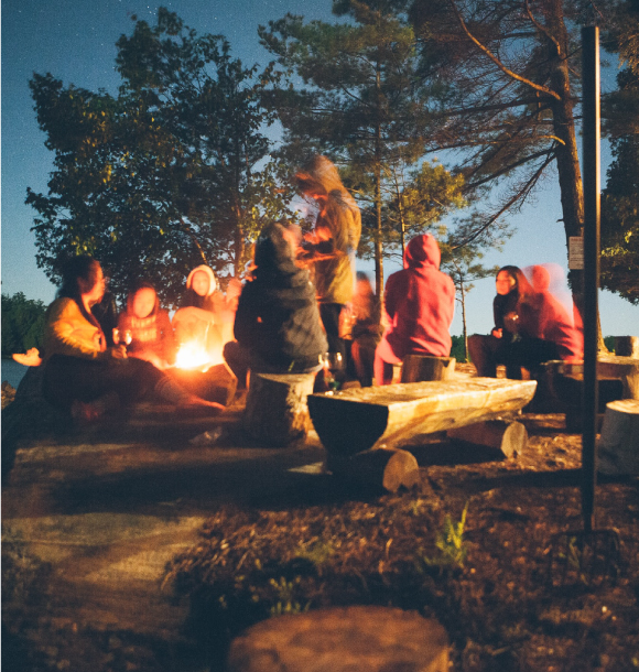 Girls sit around a bonfire